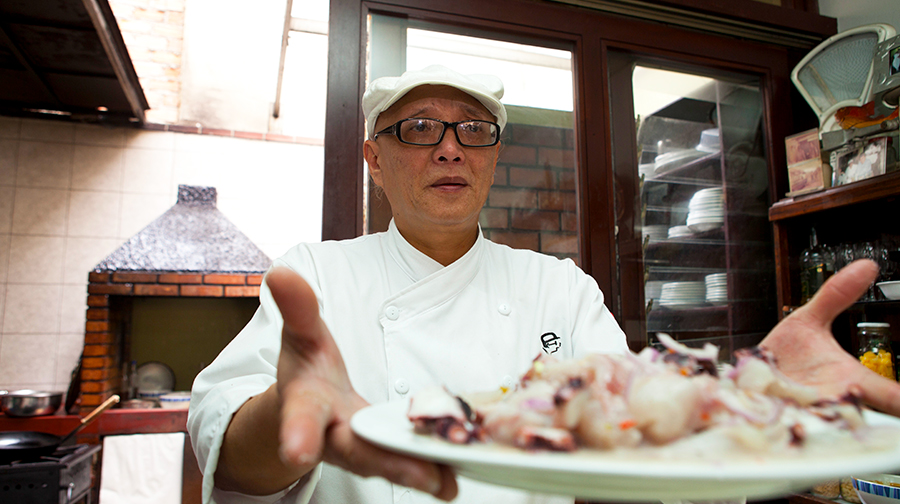Chef Javier Wong con un plato de ceviche en mano en la cocina del restaurante Sankuay.