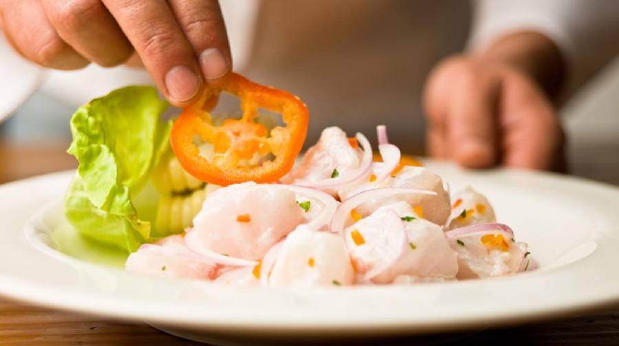 Ceviche peruano con pescado, cebolla y ají, servido en plato blanco.